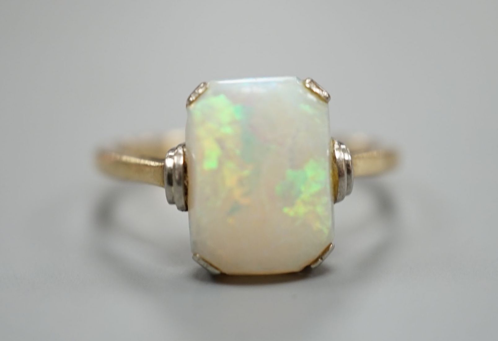 A 9ct and 'emerald' cut white opal set ring, size R, gross weight 3.2 grams.